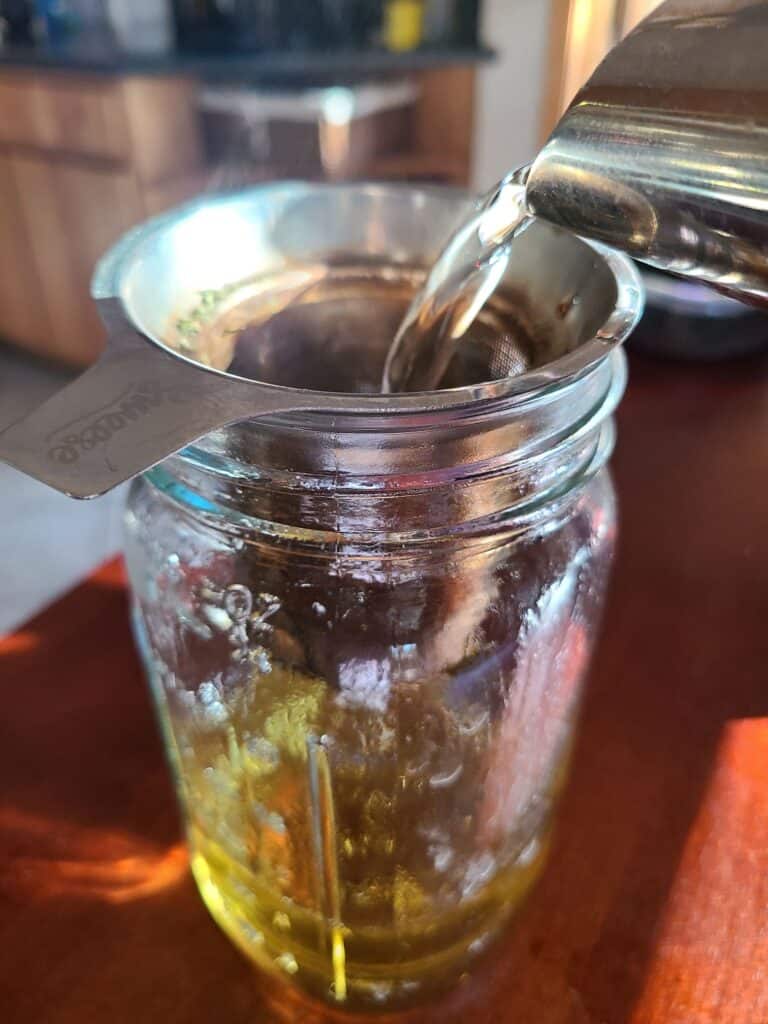 pouring water into quart jar with tea strainer